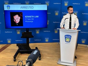 A York Regional Police officer stands at a podium with a screen showing a picture of Kenneth Law and "ARRESTED"