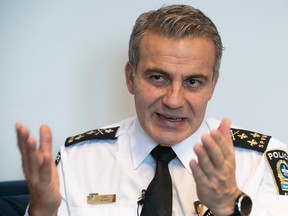 Montreal police chief Fady Dagher is seen in an office in his white uniform and black tietalkngi with his hands in front of him.