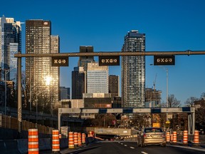 Montreal's skyline above a highway lined with orange cones