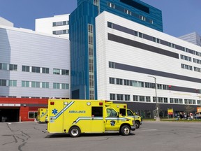 An ambulance is in the parking lot of a large building.