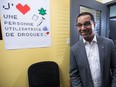 Lionel Carmant walks into a room with a poster reading "Je (heart) une personne utilisatrice de drogues"