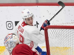 Canadiens' Filip Mesar is seen with his stick in the air as he skated by goalie Cayden Primeau in net at the Habs' practice facility in Brossard.