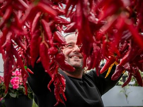 A man is seen through a large batch of red hot peppers.