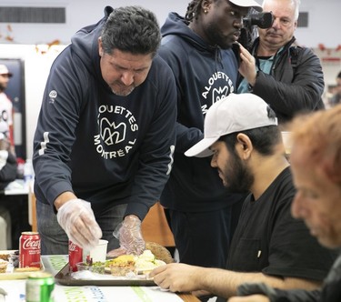 Montreal Alouettes quarterbacks coach Anthony Calvillo leans over a table as he serves Thanksgiving dinner at the Welcome Hall Mission.