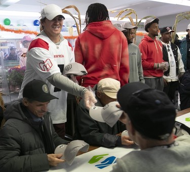 The Montreal Alouettes' Cody Fajardo smiles and gives out caps to people waiting to get Thanksgiving dinner at the Welcome Hall Mission.