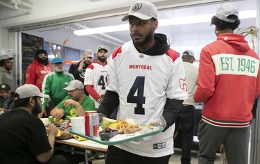 The Montreal Alouettes' Ciante Evans brings a tray of Thanksgiving dinner to a diner at the Welcome Hall Mission.