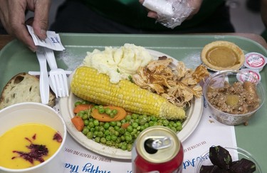 A tray of food includes a plate of turkey with peas, corn and potatoes, alongside other dishes.