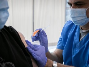 A health care worker injects a vaccine into an arm using a syringe
