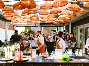 Servers work with a crowd at people from behind a square bar.
