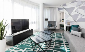 A white and grey room with green accents and a large-screen TV and sofa.