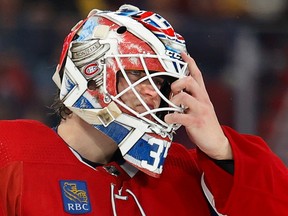 Canadiens goalie Sam Montembeault is seen in a close-up shot readjusting his mask with his left hand.