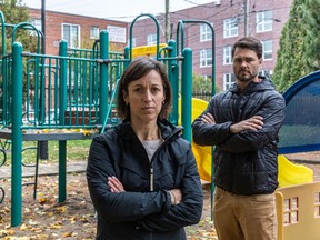 A woman and man stand in front of a children's playground.