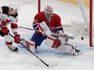 A puck goes by Canadiens goaltender Cayden Primeau in nets as New Jersey Devils' Timo Meier skates by