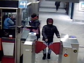 A man bundled up for winter walks through a turnstile at a metro station in a still from an elevated surveillance camera