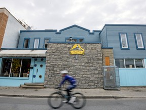 A cyclist rides past a blue and brick restaurant.