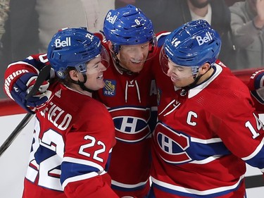 Three Canadiens players embrace while smiling
