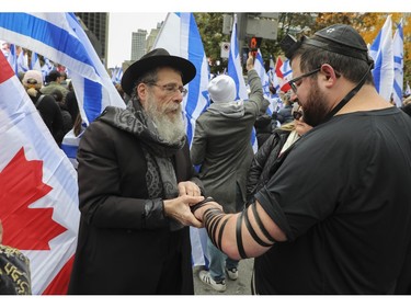 Rabbi Zushe Silberstein wraps tefillin straps around the left arm of Brandon Silverman at a rally in Montreal on Sunday, Oct. 28, 2023, that called for the release of hostages being held by Hamas.