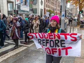 A protester holds a sign that says: Students Before Profit