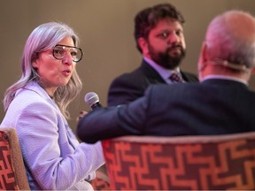 Marie-Claude Léonard speaks into a microphone while she and Eric Alan Caldwell look at Michel Leblanc, whose back is to the camera