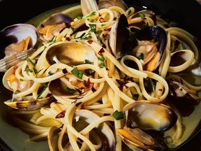 A linguine and crab dish is plated in a black pasta bowl.
