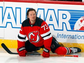 Devils' Tyler Toffoli is seen stretching his legs on the ice with both hands holding his stick parallel to the ice.