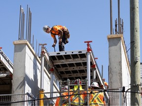 Construction workers work on a platform between two pillars while building a condo project.