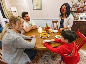 A mother and son interact with two police recruits at their dining room table.