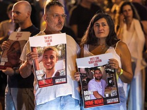 People hold signs showing two of the Israeli hostages held by Hamas since their Oct. 7 attack on Israel, during a protest calling for a ceasefire and the release of hostages, in Tel Aviv on Saturday, Oct. 28, 2023.