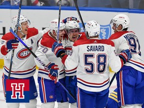 Canadiens players in white jerseys celebrate on the ice