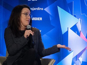 Evelyne Beaudin gestures while speaking into a microphone during a panel discussion