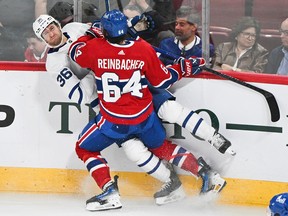 David Reinbacher checks Toronto Maple Leafs' Josiah Slavin into the boards