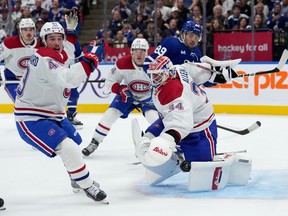 Three Canadiens players look toward the puck beside the net during a game