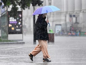A person holds an umbrella as they cross the street during a rain storm