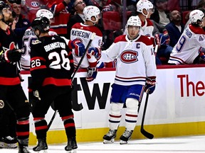 Nick Suzuki high fives players on the Canadiens bench after scoring a goal as dejected Senators players skate away