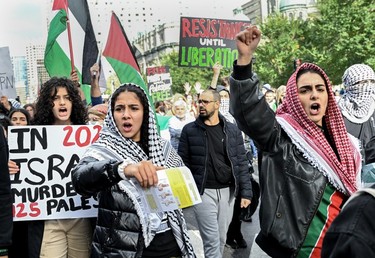 Protestors march down a street holding up signs calling for the liberation of Palestine