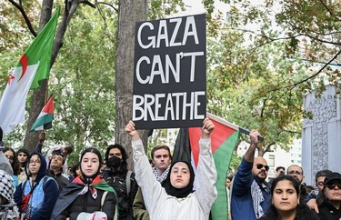 A woman holds a "Gaza can't breathe" sign surrounded by protestors with Palestinian flags