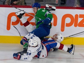 Laval Rocket's William Trudeau and Emil Heineman lie on the ice tangled up with Abbotsford's Danila Klimovich