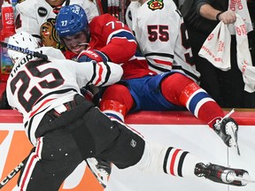 Kirby Dach falls backwards into the Chicago Blackhawks bench, pushed by Jarred Tinordi