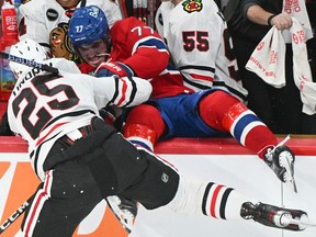 Canadiens' Kirby Dach (77) is dumped into the the Chicago Blackhawks bench by Blackhawks' Jarred Tinordi in Montreal on Saturday, Oct. 14, 2023.