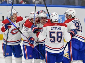 Canadiens players in white jerseys celebrate on the ice