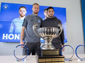 Jonathan Sirois and Mathieu Choinière stand behind a trophy posing for pictures