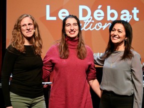 Christine Labrie, Émilise Lessard-Therrien and Ruba Ghazal stand together and smile on a debate stage