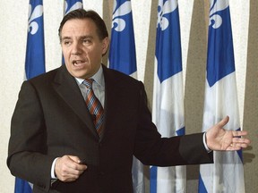 A younger François Legault gestures standing in front of Quebec flags