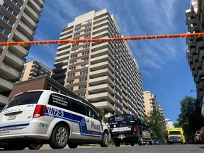 An apartment building is seen in the background behind a police vehicle and orange caution tape