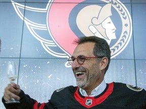 Smiling new owner Michael Andlauer dons a Senators jersey during a press conference.