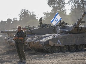 Israeli soldiers work on a tank at a staging area near the border with the Gaza Strip, in southern Israel, on Friday, Oct. 20, 2023.