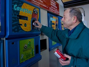 A man puts beverage cans into a collection machine