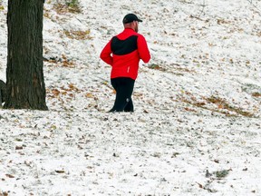 A man running on a path surrounded by a light dusting of snow on the ground