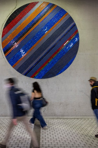 Transit users walk past the circular mosaic at the Peel Metro station in Montreal