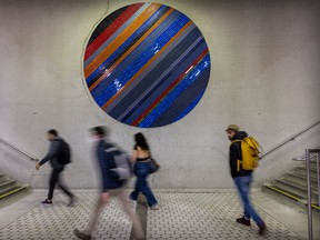 Transit users walk past the circular mosaic at the Peel Metro station in Montreal